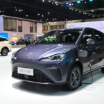 A NETA V-II electric city car on display at an auto show, plugged in for charging